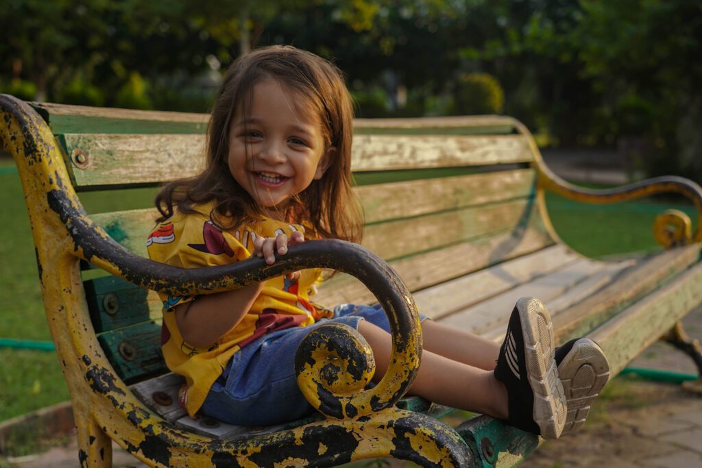Childrens Photography 2025 9 Children Photography(Childhood Photography) saeting on Woodern bench and smiling in garden